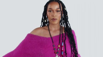 a woman with dreadlocks wearing a pink sweater