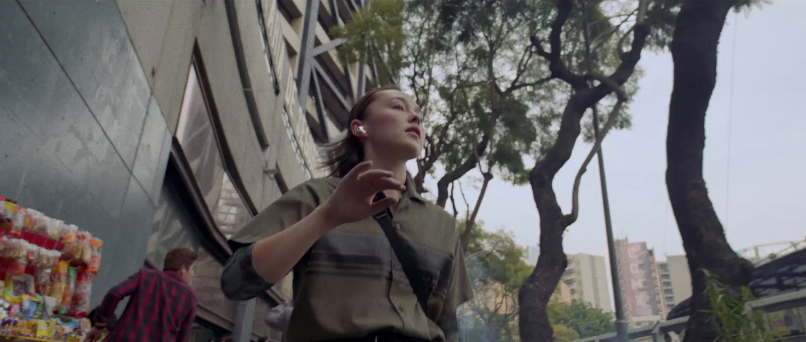 a woman walking down a street next to a tall building