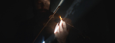 a man holding a violin in the dark