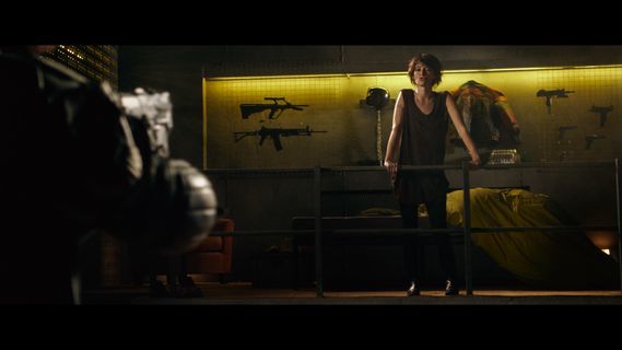 a woman standing in a room with guns