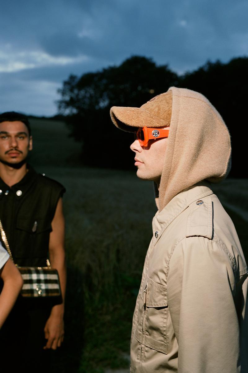 a man wearing a hood and sunglasses standing next to another man