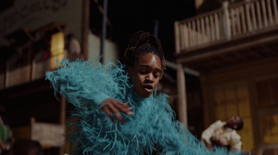 a woman in a blue feathered dress standing in front of a building