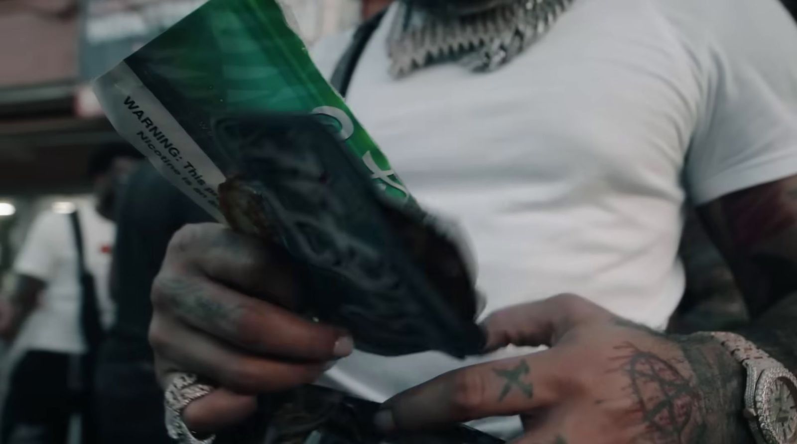 a tattooed man holding a package of cigarettes