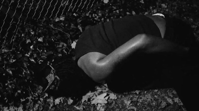 a man laying on the ground next to a fence