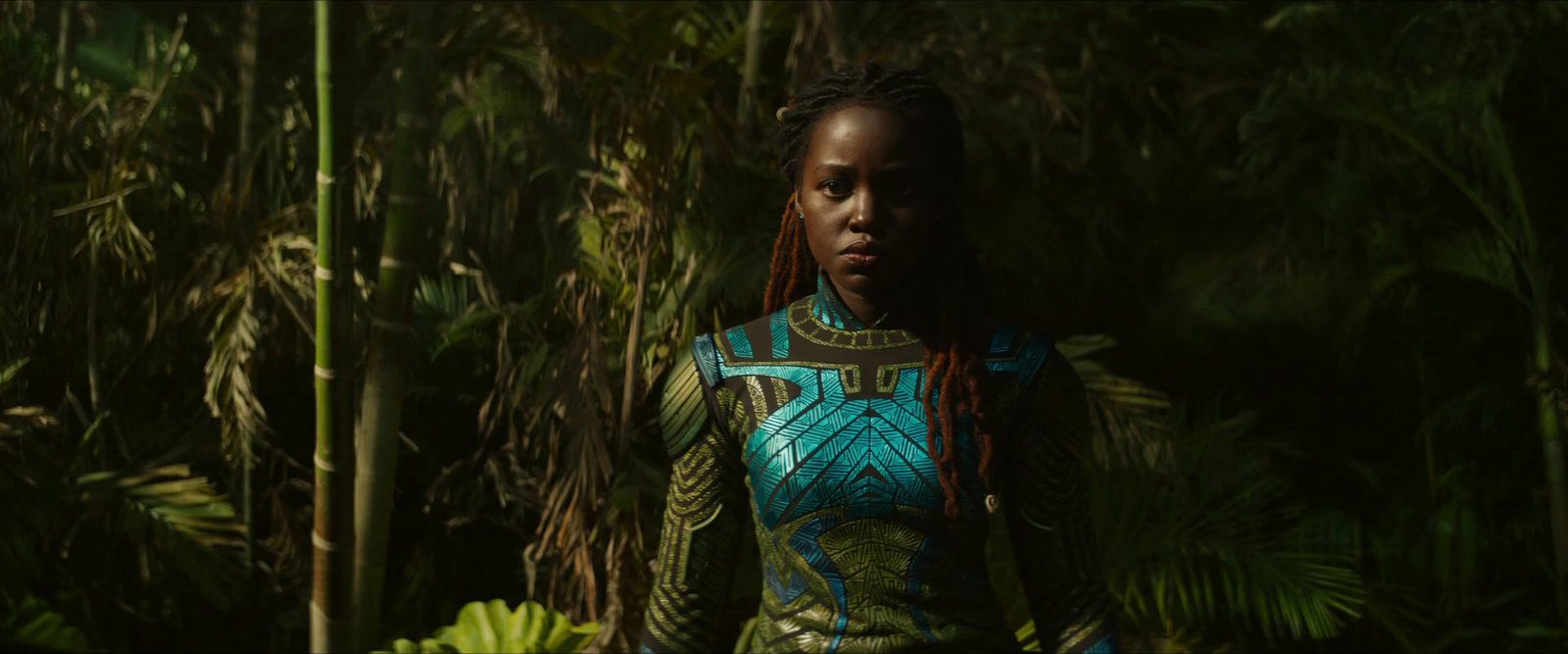 a woman with dreadlocks standing in a forest