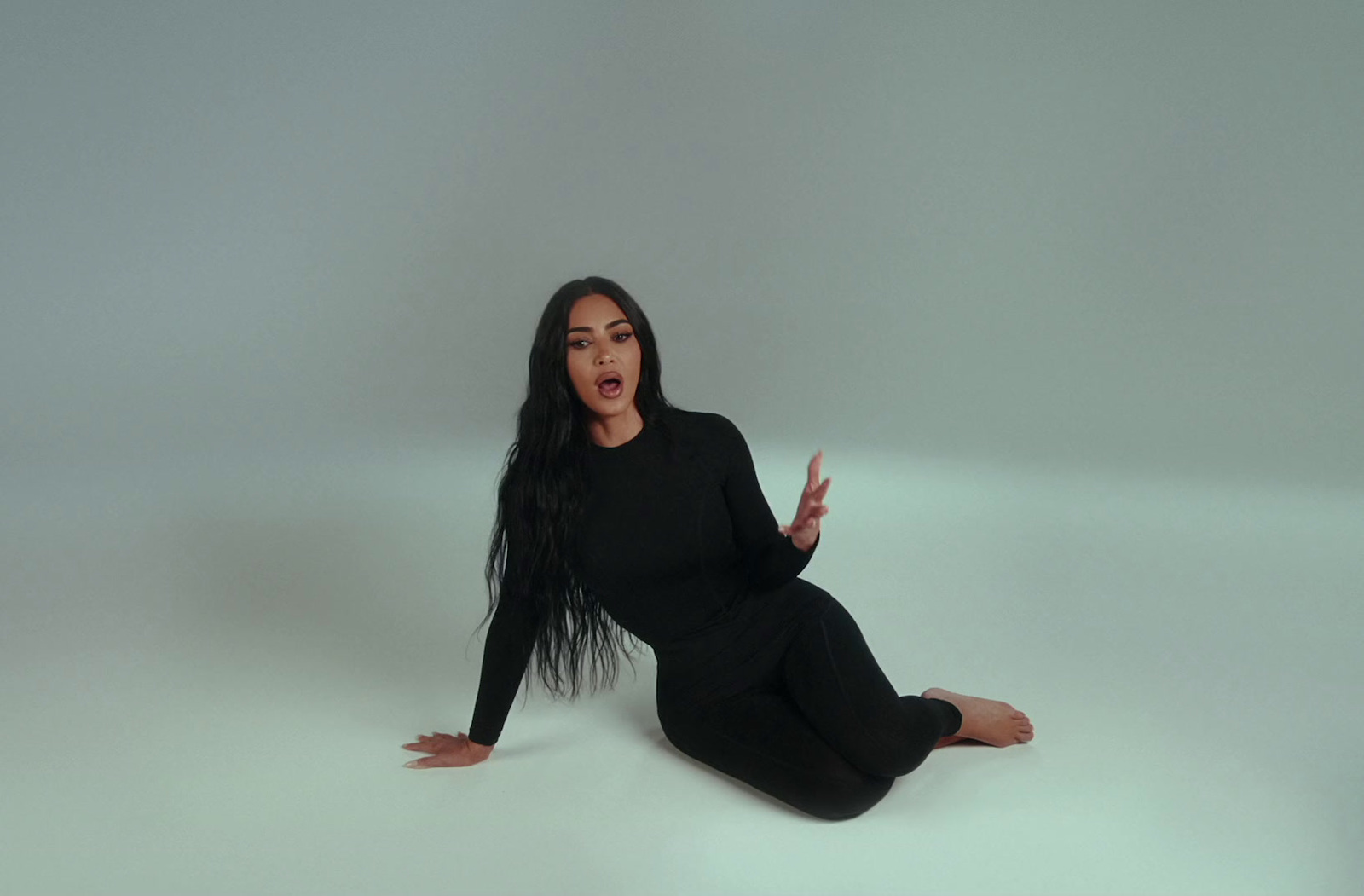 a woman sitting on the floor with her hands out