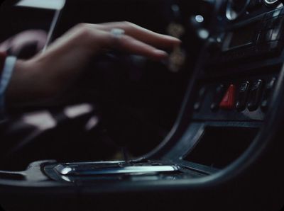 a person driving a car with their hand on the steering wheel