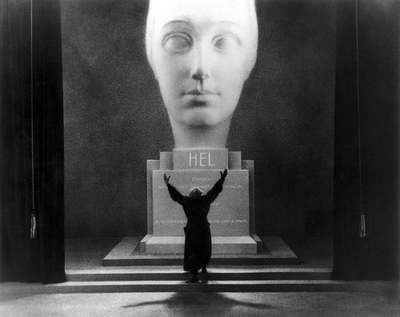 a black and white photo of a person standing in front of a head