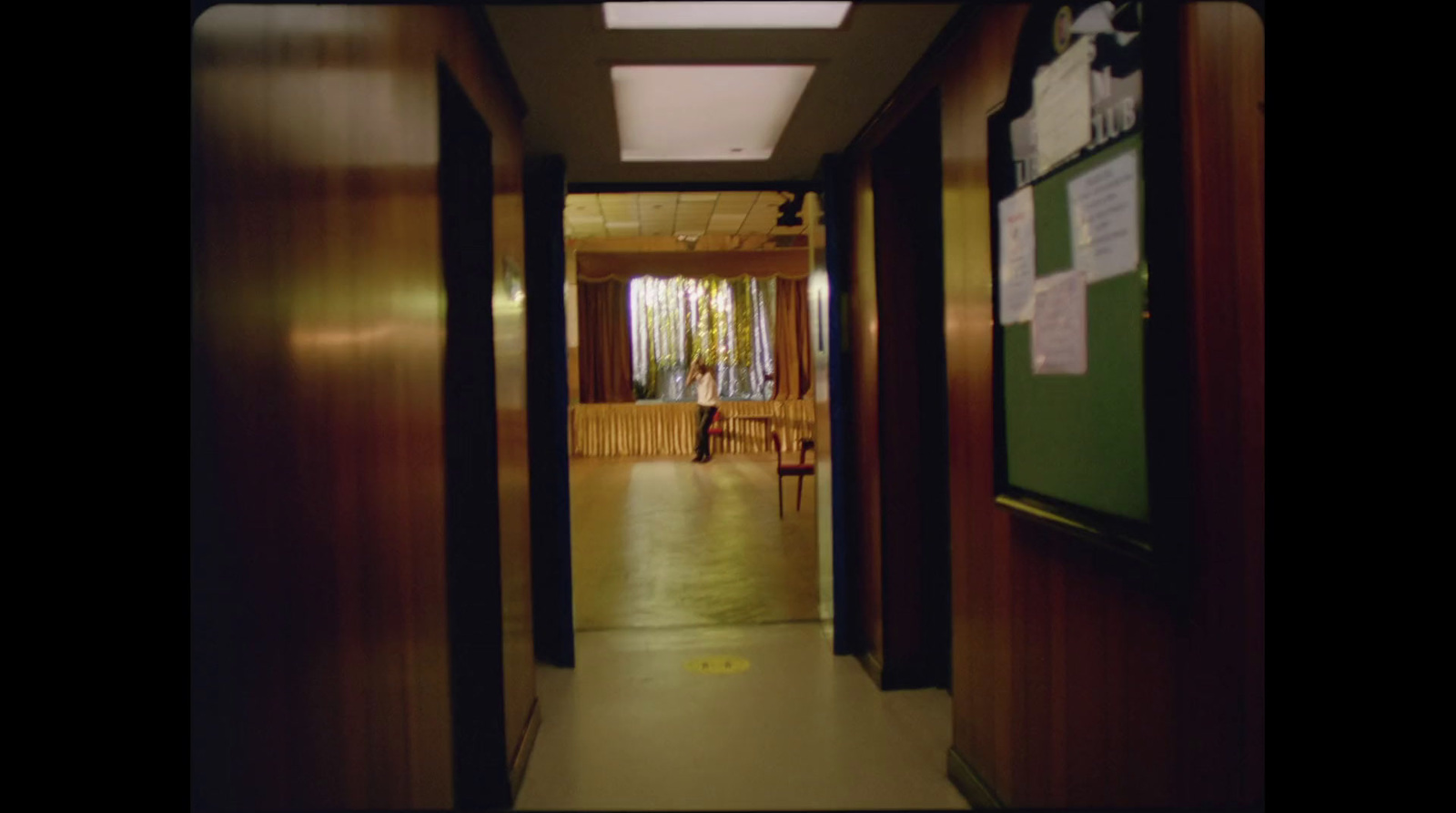 a long hallway with wooden walls and a green board on the wall