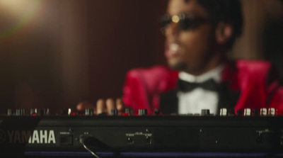 a man in a red jacket and bow tie playing a keyboard