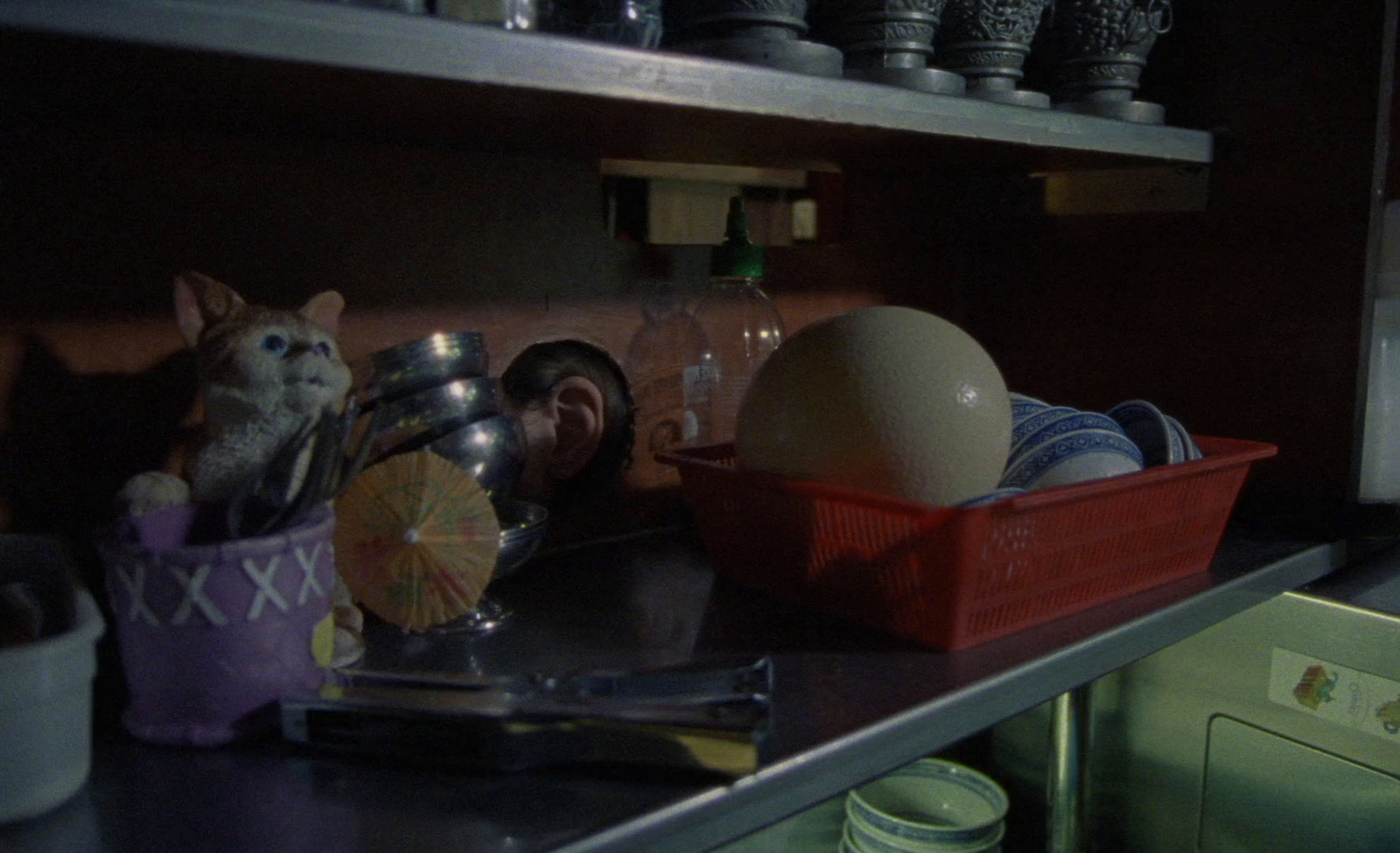 a kitchen counter with a shelf filled with dishes and utensils