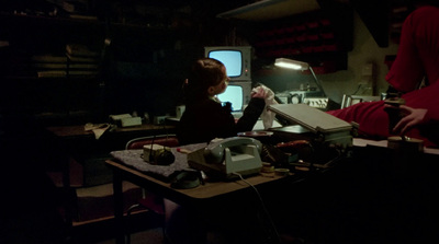 a woman sitting at a desk in a dark room