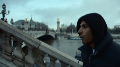 a man in a hooded jacket standing on a bridge