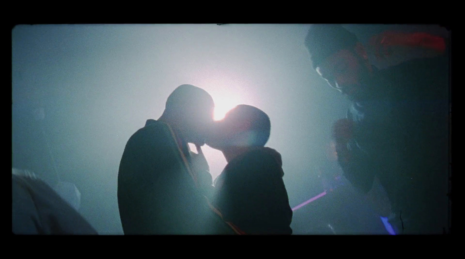 a couple of people kissing in front of a light