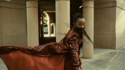 a woman in a red leather jacket is walking down the street