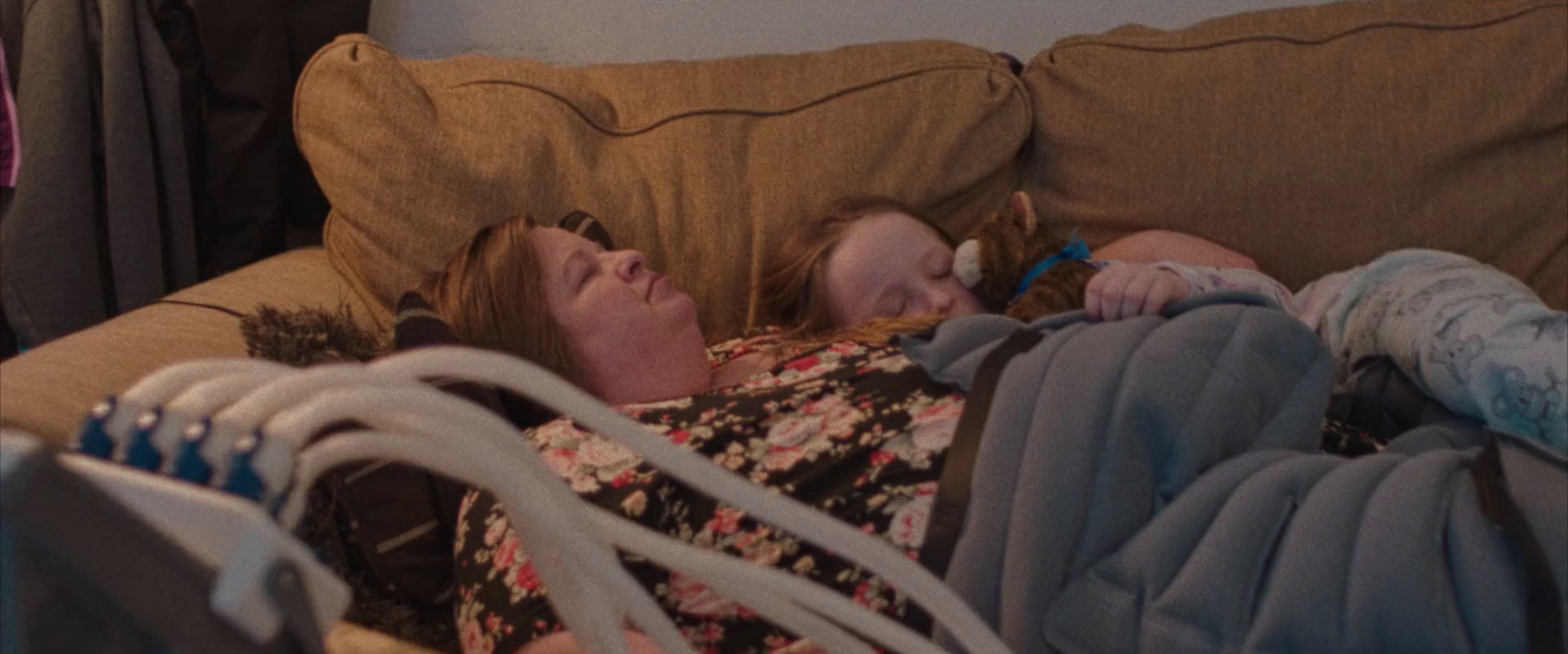 a woman laying on top of a couch next to a baby