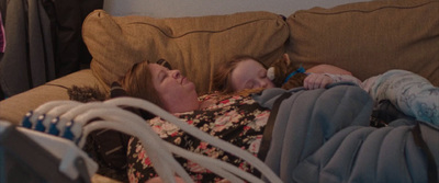 a woman laying on top of a couch next to a baby