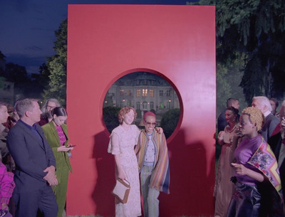 a group of people standing in front of a red sculpture