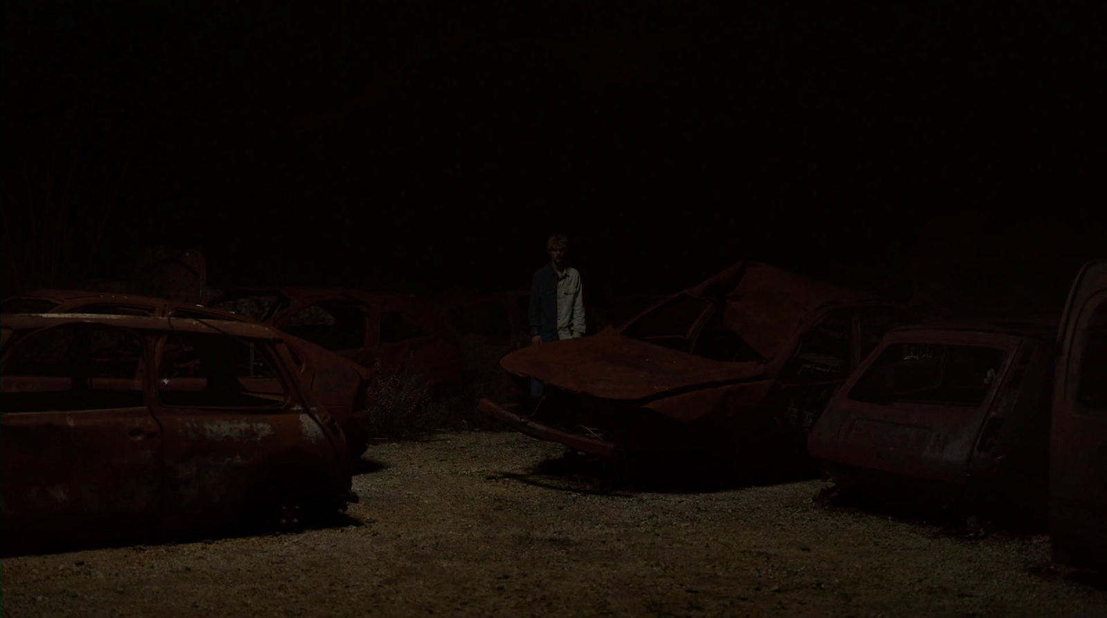 a man standing next to a bunch of wrecked cars