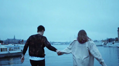 a man and a woman holding hands on a dock