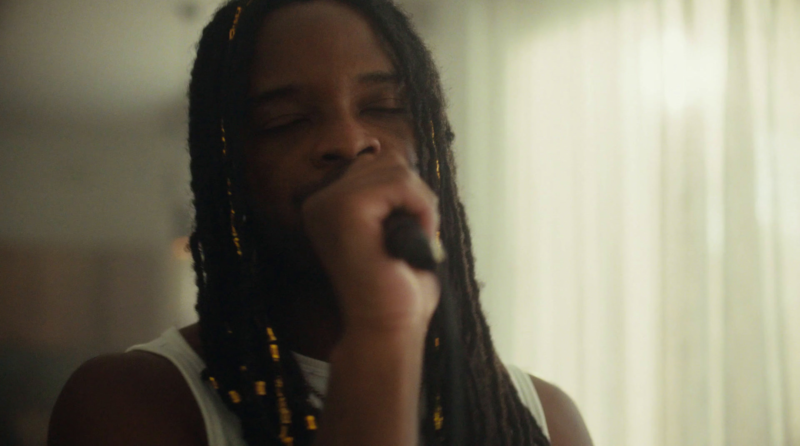 a man with dreadlocks is singing into a microphone