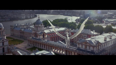 a bird flying over a city with a river in the background