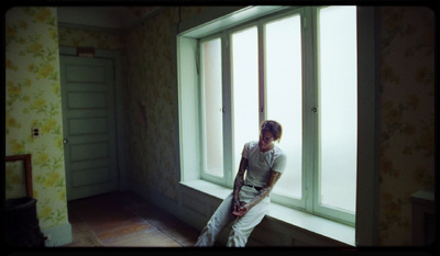 a man sitting on a window sill looking out the window