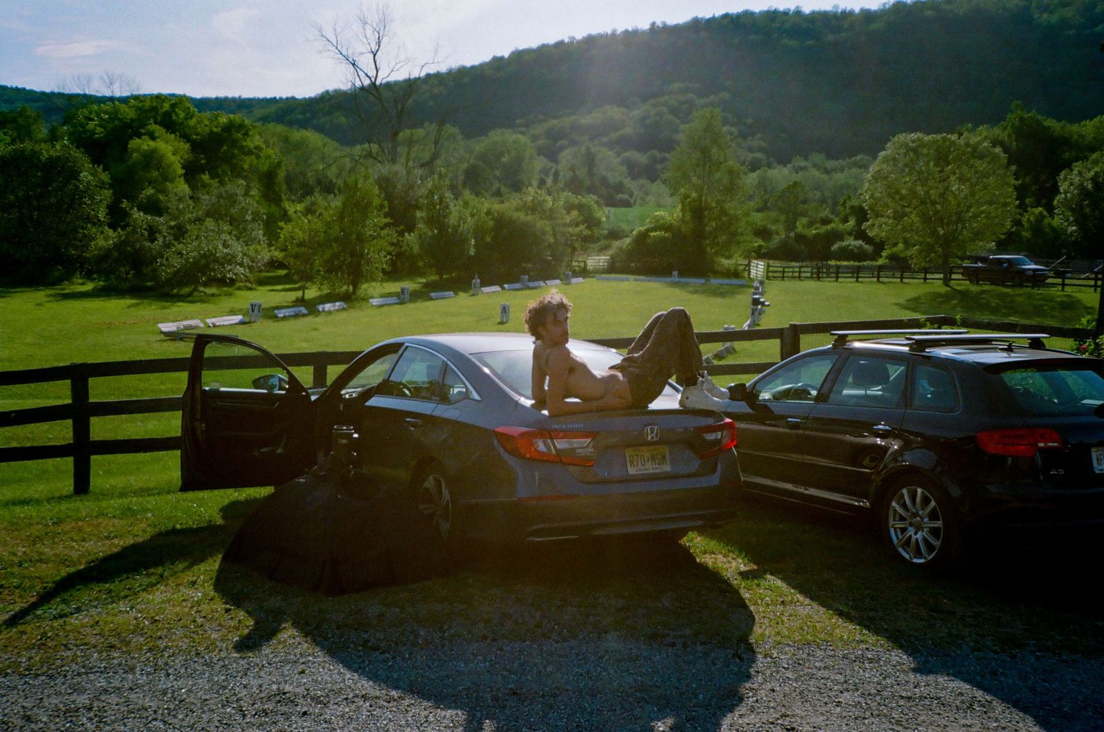 a woman sitting in the back of a car next to another car