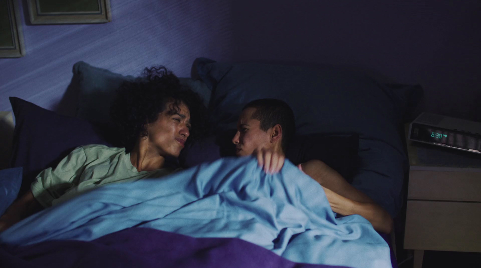 a man and a woman laying in bed under a blanket