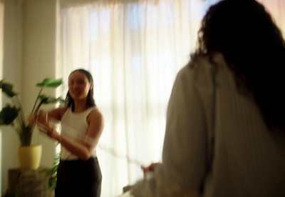 a woman standing in a living room next to a plant