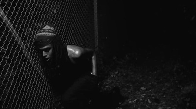 a man leaning against a fence in the dark