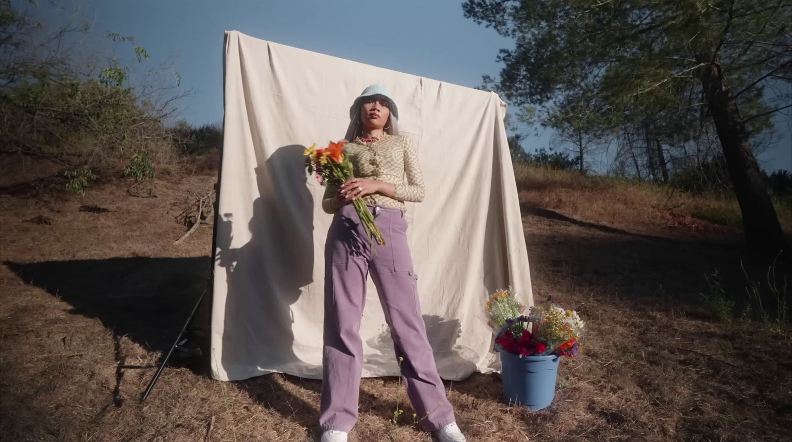 a woman standing in front of a white sheet holding flowers