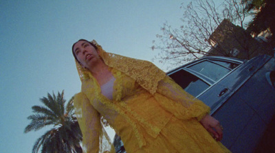 a woman in a yellow dress standing next to a car