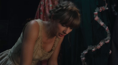 a woman in a dress looking down at a cake