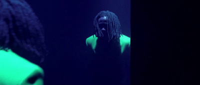 a man with dreadlocks standing in a dark room