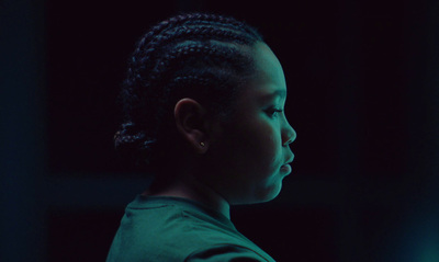 a young girl with braids in a dark room