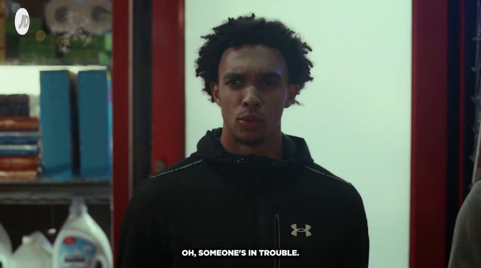 a man in a black hoodie standing in front of a mirror