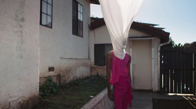 a woman in a pink dress standing outside of a house