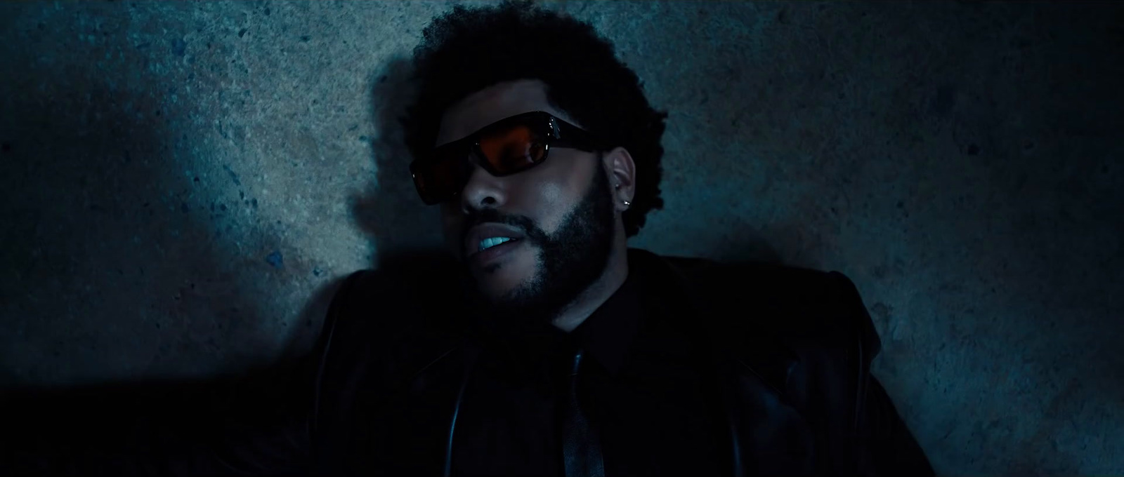 a man with a beard and sunglasses in a dark room