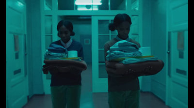 two young women carrying blankets in a hallway