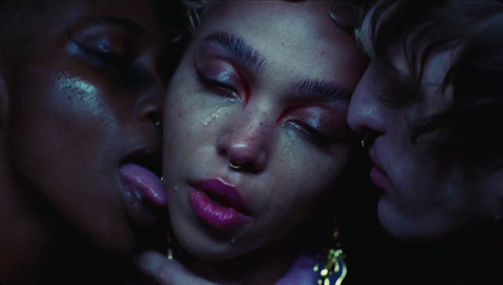 a group of women kissing each other in the dark