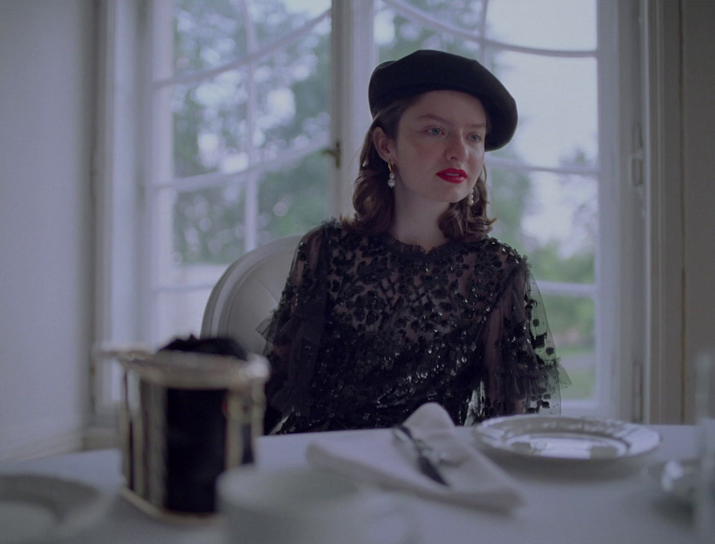 a woman sitting at a table in front of a window