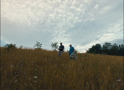 a couple of people standing on top of a grass covered field