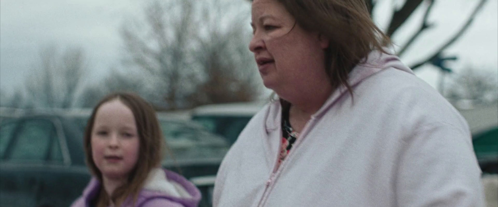 a woman standing next to a little girl in a parking lot