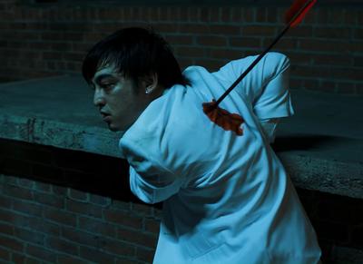 a man holding a red umbrella standing next to a brick wall