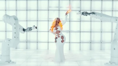 a woman in a white body suit holding a flame