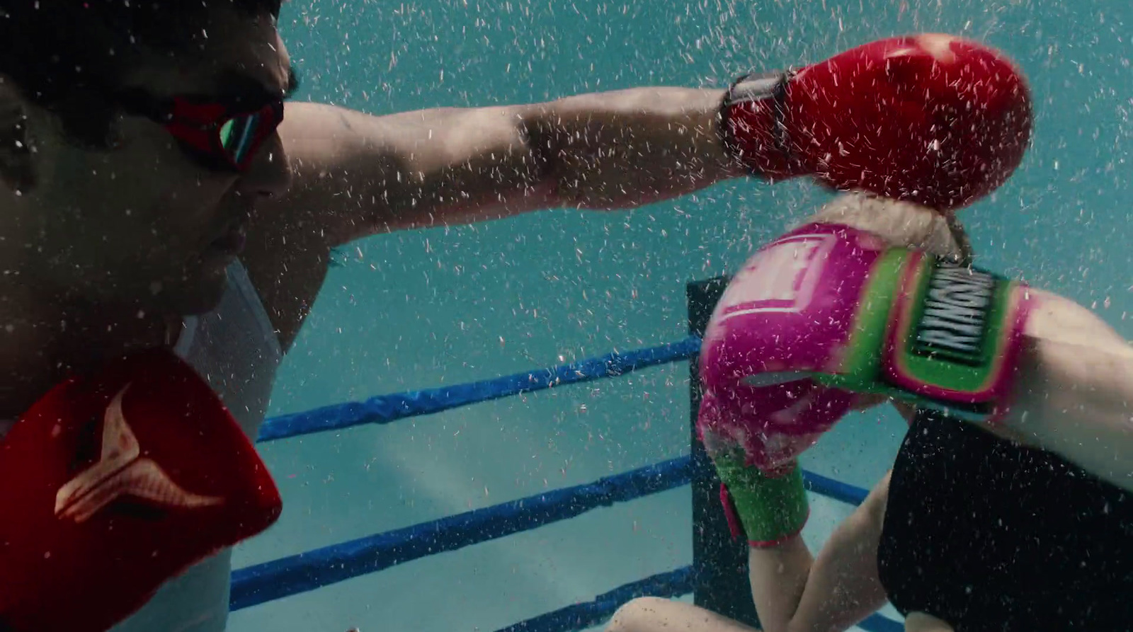 a man wearing a red boxing glove next to a woman in a pink boxing suit