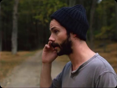 a man with a beard talking on a cell phone