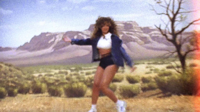 a woman is dancing in a field with mountains in the background