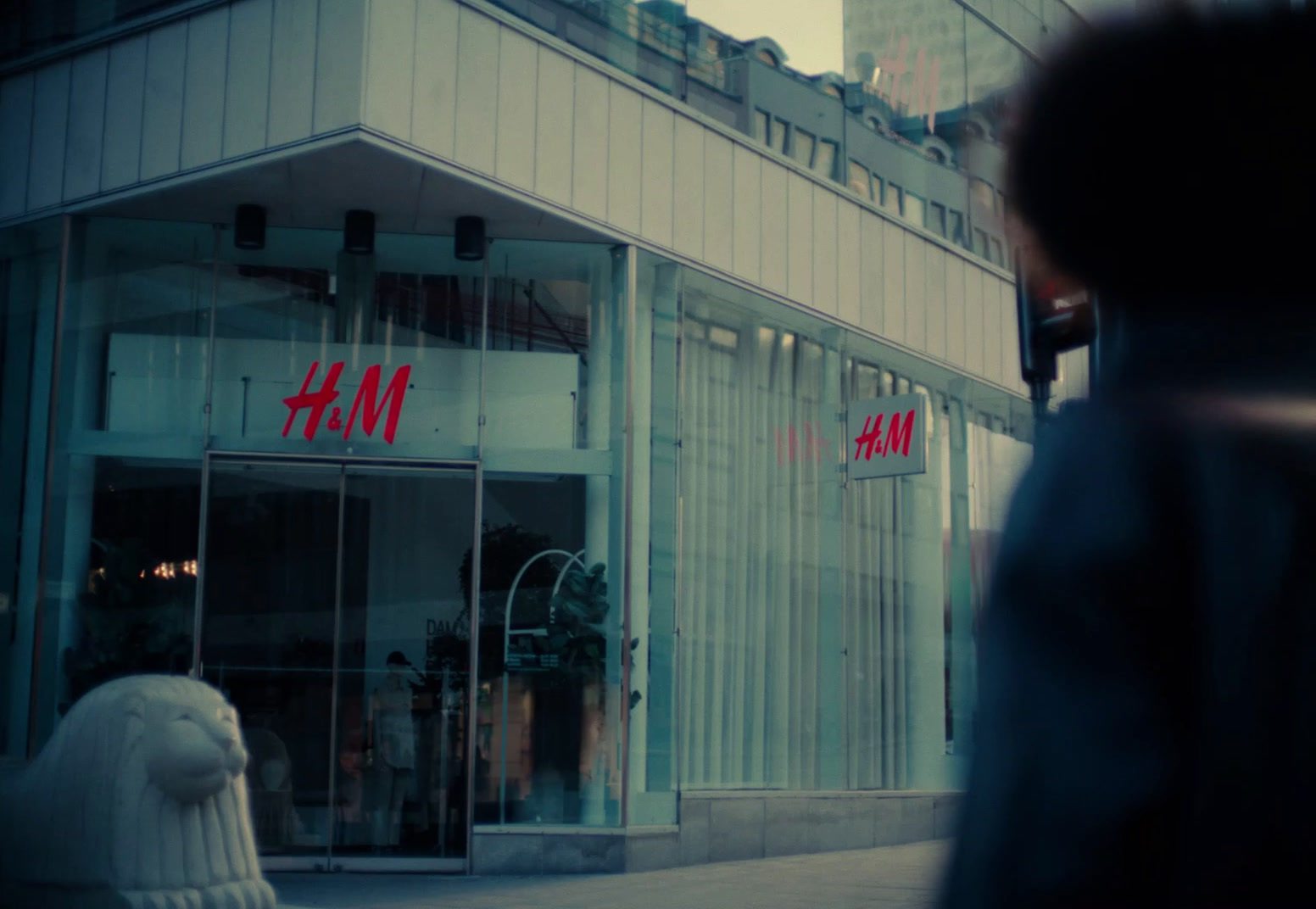 a man walking down a street past a tall building